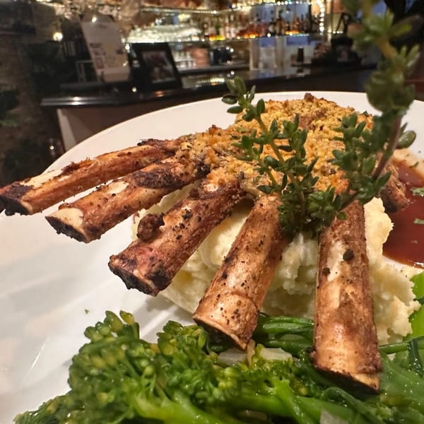 Grilled lamb chops with mashed potatoes, broccoli, and gravy, garnished with herbs at Nirvana.