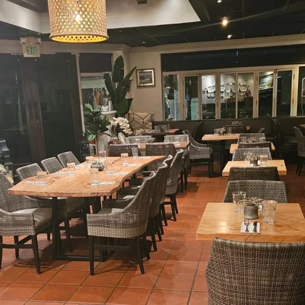 Interior of Nirvana by Chef Lindsay, an American restaurant with wooden tables, woven chairs, and warm lighting.