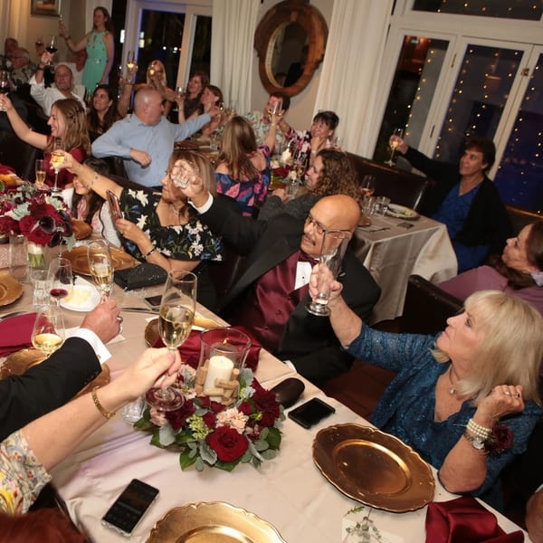 Guests at Nirvana by Chef Lindsay raising glasses for a toast at a festive dinner event.