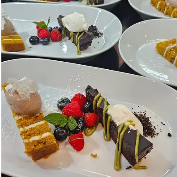Plates of layered cake, chocolate dessert with matcha drizzle, berries, and ice cream.
