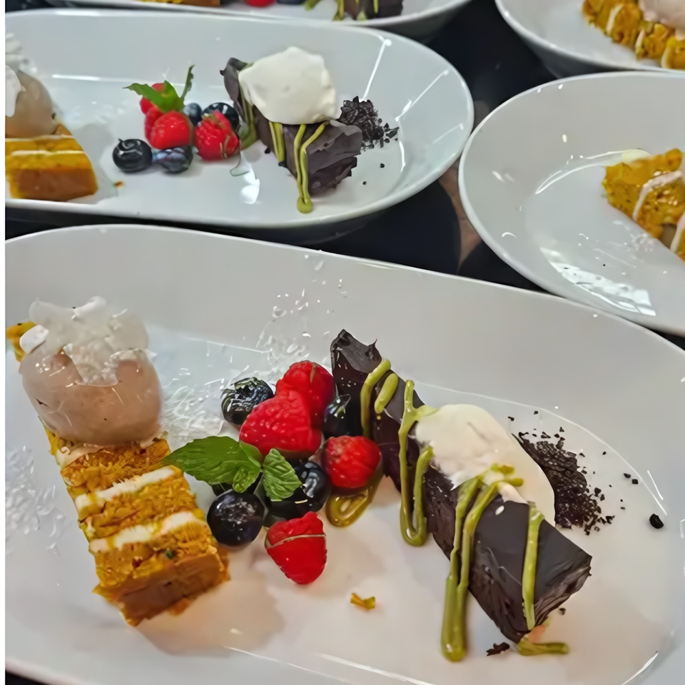 Plates of layered cake, chocolate dessert with matcha drizzle, berries, and ice cream.