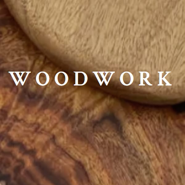 The word "WOODWORK" in white text against a blurred background of light and dark brown wood grain.